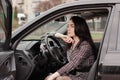 portrait of attractive brunette in grey checkered dress in a black car. girl in automobile. business woman