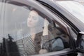 portrait of attractive brunette in grey checkered dress in a black car. girl in automobile. business woman