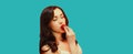 Portrait of attractive brunette sexy woman enjoying taste of fresh strawberry on blue background