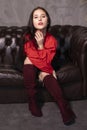 Portrait of attractive brunette woman in red blouse and black skirt sitting on leather couch in a vintage cafe. st valentines day Royalty Free Stock Photo