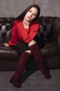 Portrait of attractive brunette woman in red blouse and black skirt sitting on leather couch in a vintage cafe. st valentines day Royalty Free Stock Photo