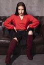 Portrait of attractive brunette woman in red blouse and black skirt sitting on leather couch in a vintage cafe. st valentines day Royalty Free Stock Photo