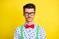 Portrait of attractive calm serious guy wearing specs print shirt isolated over bright yellow color background