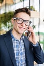 Portrait of attractive caucasian man in casual shirt and glasses talking on cellular phone at workplace. Royalty Free Stock Photo