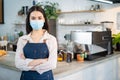 Portrait of attractive Caucasian waitress wearing protective mask to prevent from Covid-19 pandemic at cafe. Young beautiful girl Royalty Free Stock Photo