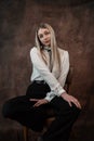 Portrait of caucasian woman wearing white blouse sitting at chair isolated dark background Royalty Free Stock Photo