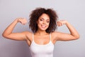 Portrait of attractive, charming, athletic, pretty, strong, positive woman showing her biceps with raised arms, looking at camera Royalty Free Stock Photo