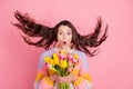 Portrait of attractive cheerful amazed girl holding in hands tulips wind blowing spring event isolated over pink pastel Royalty Free Stock Photo