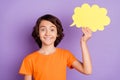 Portrait of attractive cheerful boy holding in hand cloud copy empty space message isolated over violet purple color