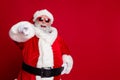 Portrait of attractive cheerful confident Santa pointing at you copy space select isolated over bright red color