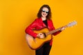 Portrait of attractive cheerful famous wavy-haired girl playing guitar singing isolated bright yellow color background Royalty Free Stock Photo