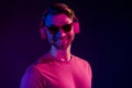 Portrait of attractive cheerful funny guy listening bass sound single pop funk isolated over dark neon light violet