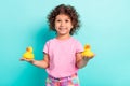 Portrait of attractive cheerful girl holding on palms two rubber duck isolated over bright teal turquoise color Royalty Free Stock Photo