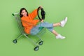 Portrait of attractive cheerful girl riding cart holding streering wheel fooling isolated over bright green color Royalty Free Stock Photo