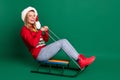 Portrait of attractive cheerful girl riding sledges having fun good mood isolated over green color background