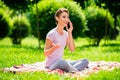 Portrait of attractive cheerful girl sitting on veil talking on phone resting free time on fresh air green grass Royalty Free Stock Photo