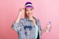 Portrait of attractive cheerful girl tennis player touching cap drinking water isolated over pink pastel color Royalty Free Stock Photo