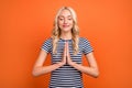 Portrait of attractive cheerful grateful hopeful wavy-haired girl praying sincerely isolated over bright orange color