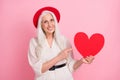 Portrait of attractive cheerful grey-haired retired pensioner elderly woman demonstrating heart amour isolated over pink