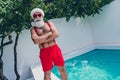 Portrait of attractive cheerful grey-haired Santa folded arms having fun spending eve advent x mas december poolside Royalty Free Stock Photo