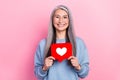 Portrait of attractive cheerful grey-haired woman granny holding like card isolated over pink pastel color background Royalty Free Stock Photo