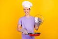 Portrait of attractive cheerful guy frying making tasty yummy meal gourmet recipe isolated over bright yellow color