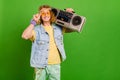 Portrait of attractive cheerful guy hippie holding tape player good mood rest isolated over bright green color