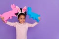 Portrait of attractive cheerful pre-teen girl holding bunnies playing toys isolated over bright purple violet color Royalty Free Stock Photo