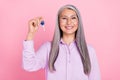 Portrait of attractive cheerful successful gray-haired woman holding house key isolated over pink pastel color Royalty Free Stock Photo