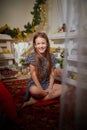 Portrait of attractive cheerful young girl resting festal day december winter in room decorated for Christmas. Child in Royalty Free Stock Photo