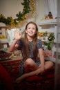 Portrait of attractive cheerful young girl resting festal day december winter in room decorated for Christmas. Child in Royalty Free Stock Photo