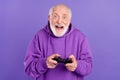 Portrait of attractive cheery addicted grey-haired man playing game having fun isolated over bright violet purple color Royalty Free Stock Photo