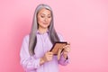 Portrait of attractive cheery dreamy gray-haired woman looking at photo picture isolated over pink pastel color