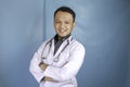 Portrait of an attractive confident male doctor, friendly smiling arms crossed wear white lab coat stethoscope isolated blue color Royalty Free Stock Photo