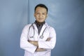 Portrait of an attractive confident male doctor, friendly smiling arms crossed wear white lab coat stethoscope isolated blue color Royalty Free Stock Photo