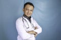 Portrait of an attractive confident male doctor, friendly smiling arms crossed wear white lab coat stethoscope isolated blue color Royalty Free Stock Photo