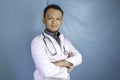 Portrait of an attractive confident male doctor, friendly smiling arms crossed wear white lab coat stethoscope isolated blue color Royalty Free Stock Photo