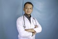 Portrait of an attractive confident male doctor, friendly smiling arms crossed wear white lab coat stethoscope isolated blue color Royalty Free Stock Photo