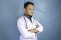 Portrait of an attractive confident male doctor, friendly smiling arms crossed wear white lab coat stethoscope isolated blue color Royalty Free Stock Photo