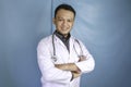 Portrait of an attractive confident male doctor, friendly smiling arms crossed wear white lab coat stethoscope isolated blue color Royalty Free Stock Photo