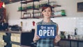 Portrait of confident woman small business owner holding We Are Open sign standing in her coffee shop and smiling Royalty Free Stock Photo