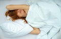 Portrait of an attractive, content, young, red-haired woman lying relaxed in bed, enjoying and snuggling Royalty Free Stock Photo