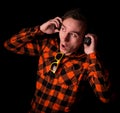 Crazy young and handsome man with headphones and modern sunglasses in stylish checkered shirt with hands on headphones