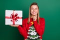 Portrait of attractive curious cheerful girl holding giftbox overthinking December tradition isolated over green color