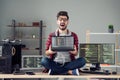 Portrait of attractive desperate crazy guy hacker sitting on table holding laptop code database at work place station