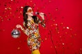 Portrait of attractive dreamy cheerful girl holding disco ball singing hit celebrating isolated over bright red color Royalty Free Stock Photo