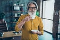 Portrait of attractive dreamy gray-haired man hr employer drinking coffee pause break at loft interior work place Royalty Free Stock Photo