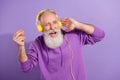Portrait of attractive elderly cheerful grey-haired man listening hit stereo dancing having fun isolated over purple Royalty Free Stock Photo