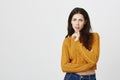 Portrait of attractive european female in yellow cropped sweater holding finger in ching while expressing dislike and Royalty Free Stock Photo