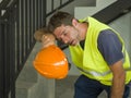 Portrait of attractive and exhausted construction worker in helmet and vest at building site taking a breath during a hard working Royalty Free Stock Photo